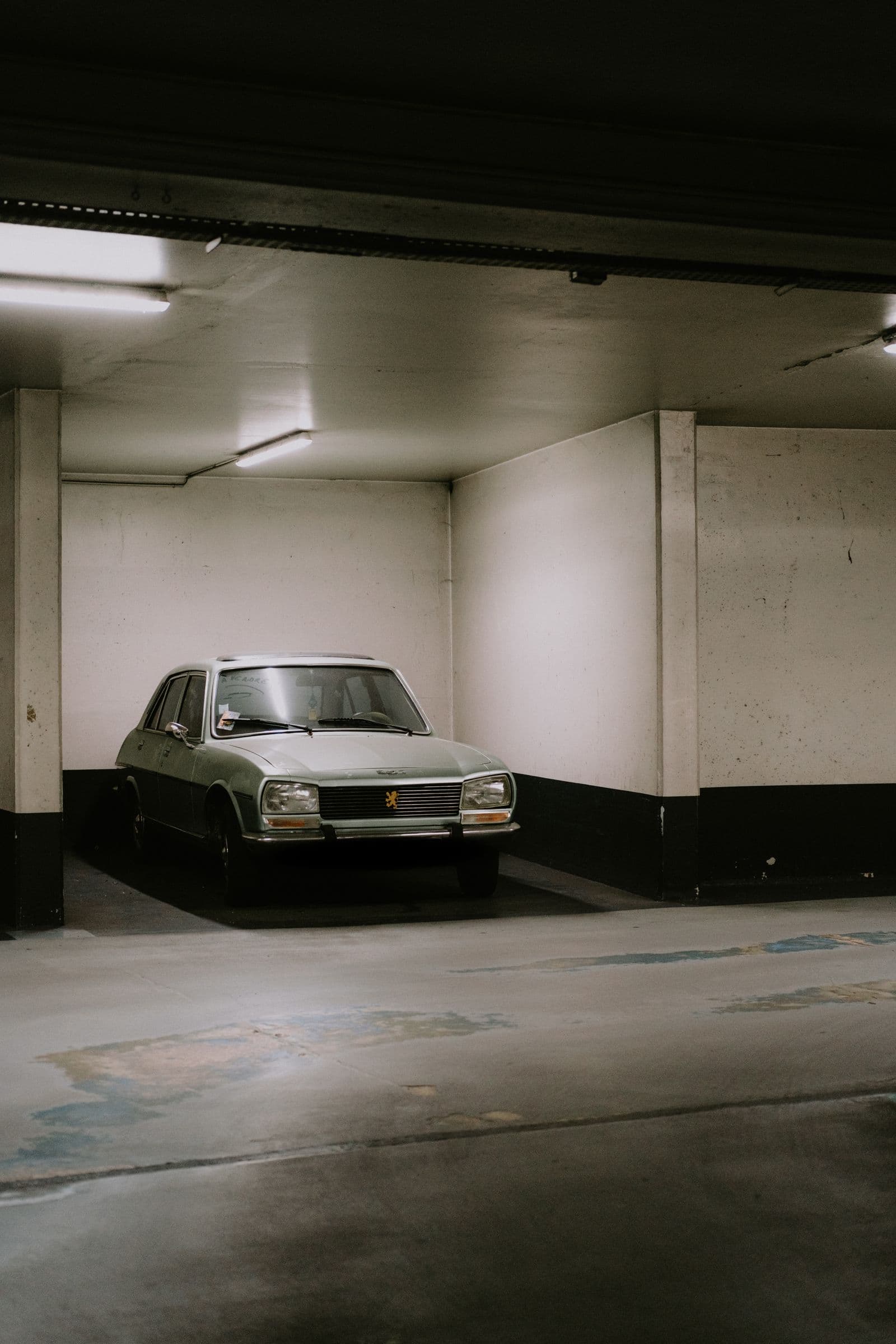 Dim garage with a stained, worn concrete floor — the typical starting point of a makeover