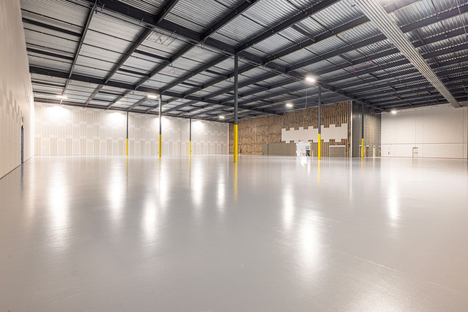 High-gloss coated floor reflecting overhead lights in a large open space — a finish example
