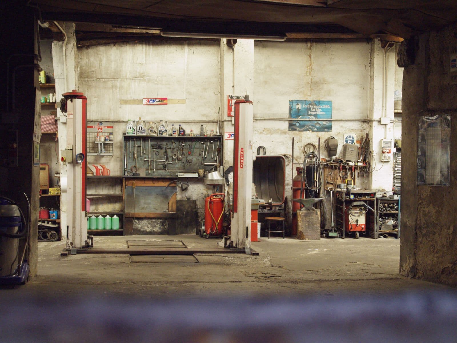Working garage with vehicle lifts, tool benches and a worn concrete floor awaiting transformation